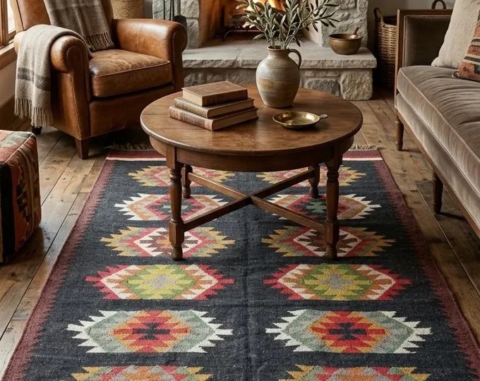 Dark area rug with rows of colourful serrated diamond medallions beneath a round wooden coffee table.
