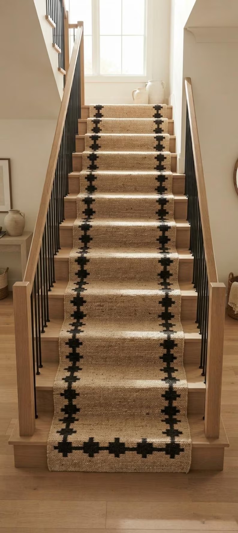 Sand-coloured stair runner with repeating black cross-shaped motifs along both borders, fitted to a light wooden staircase.
